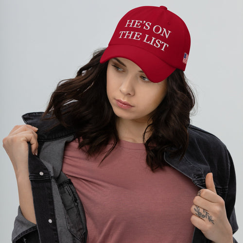 Woman wearing a red cap with text, holding a jacket against a gray background