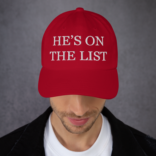 Red cap with 'HE'S ON THE LIST' text worn by a person against a gray background
